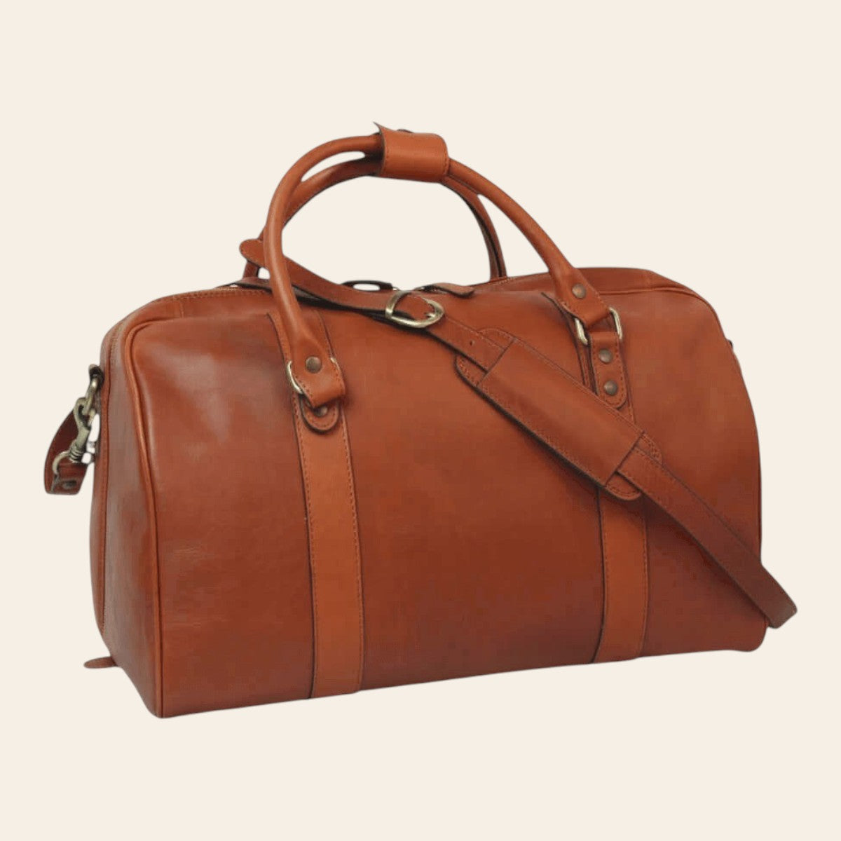 Sac de voyage en cuir cognac chaud, vue de trois quarts avec doubles poignées et bandoulière amovible