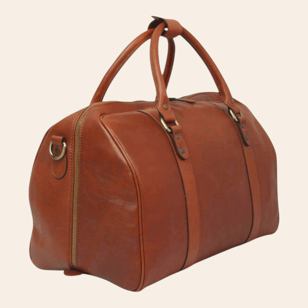 Sac de voyage en cuir cognac chaud, vue latérale de trois quarts avec zip périphérique et doubles poignées