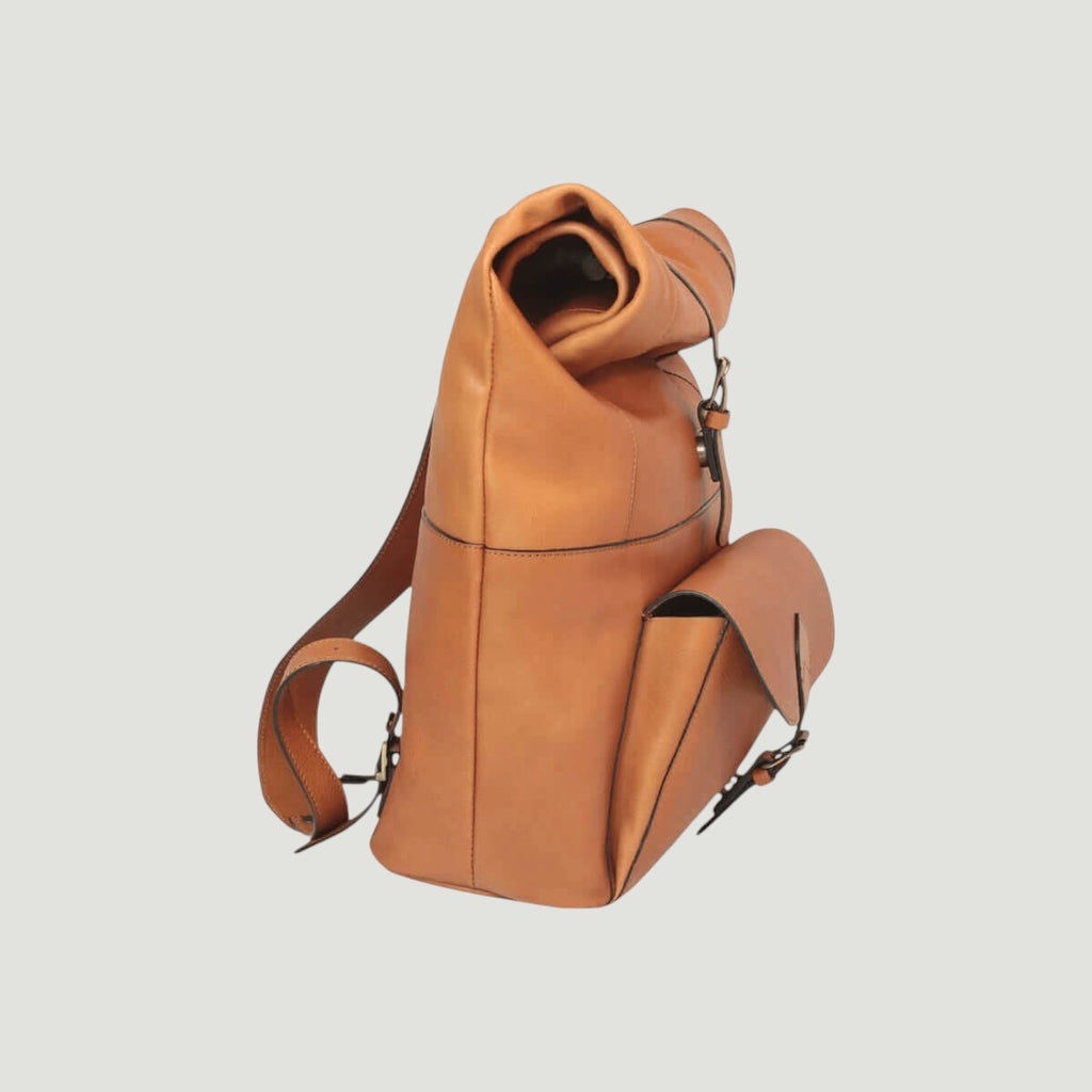 Zaino in pelle marrone con spalle e fibbie laterali; apertura superiore visibile.