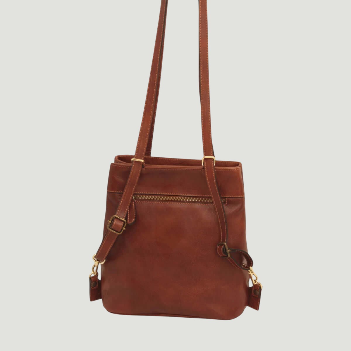 Zaino in pelle marrone con chiusura frontale a zip e due tracolle verticali.