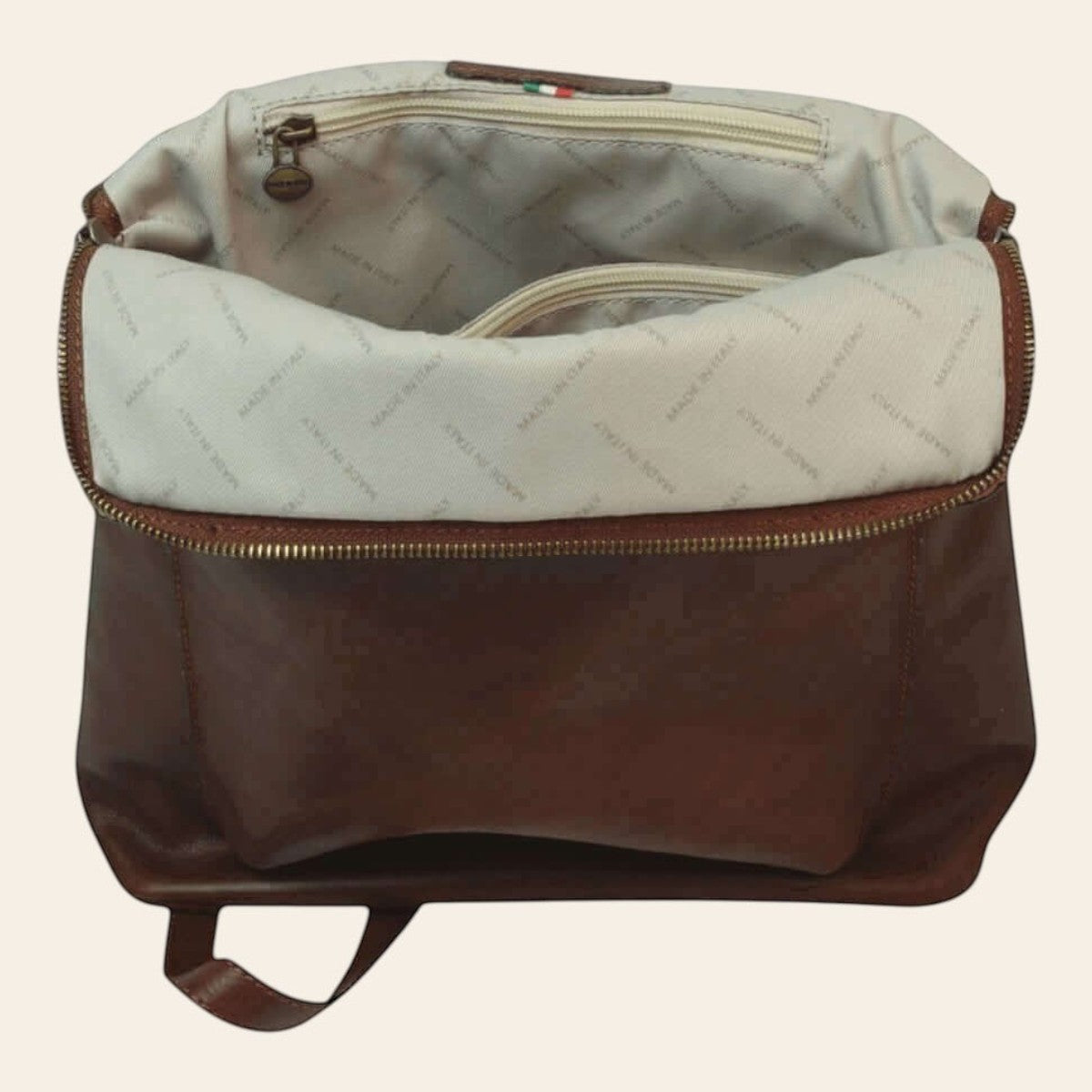 Zaino in pelle marrone con interno foderato chiaro e tasca superiore con zip