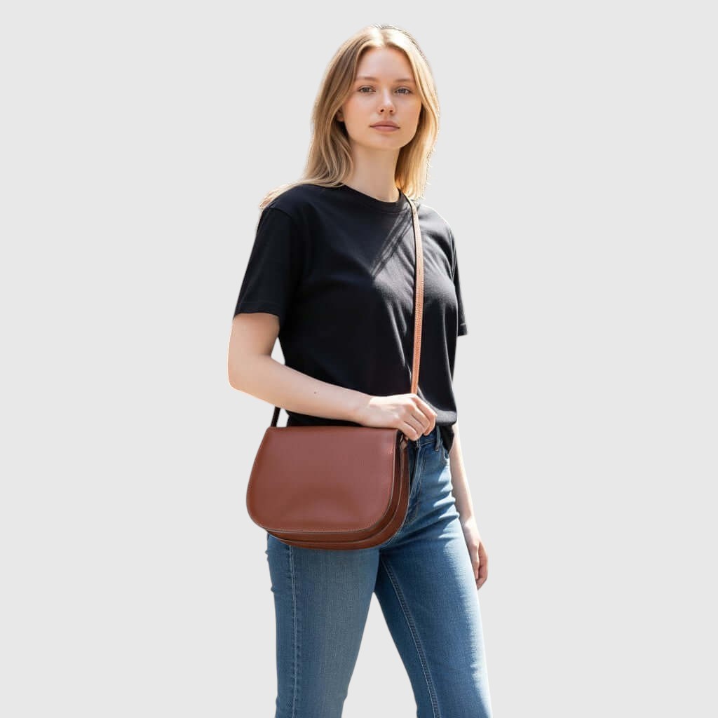 Borsa a tracolla in pelle teak con tracolla regolabile, indossata su spalla.
